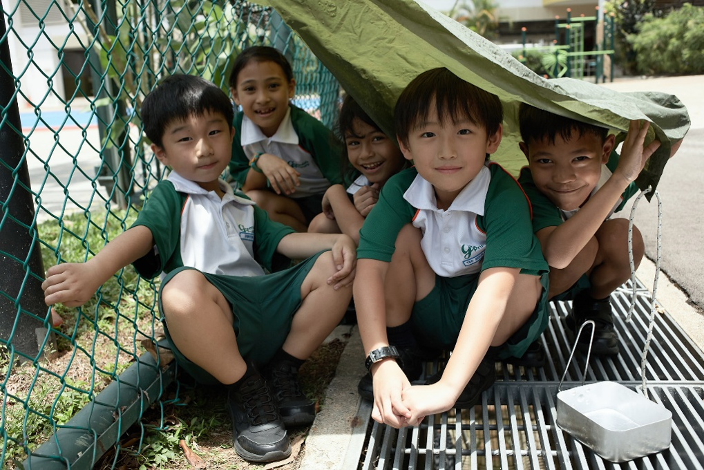 Students resting under a makeshift shelter during an outdoor learning activity.